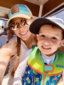 A joyful moment captured with a mother and her child on a boat, both smiling and ready for a fun day on the water, showcasing the excitement of family adventures.