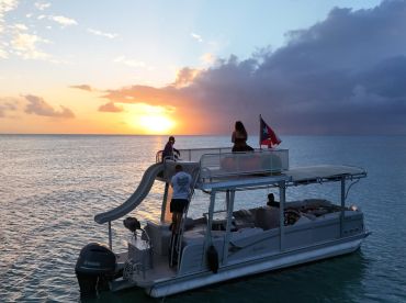 A group enjoys a stunning sunset aboard a pontoon boat, creating the perfect backdrop for memorable moments on the water.