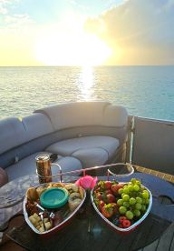A beautifully arranged spread of fruits, cheeses, and snacks on a boat table, perfect for enjoying a sunset cruise or a relaxing day on the water.
