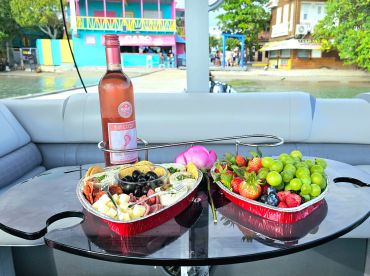 A beautifully arranged charcuterie platter and a bottle of pink moscato set on a boat table, perfect for enjoying gourmet snacks while cruising.