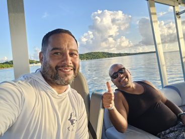 Two friends enjoy a relaxing moment on a boat, smiling and taking in the beautiful water views — perfect for a day out on the water.