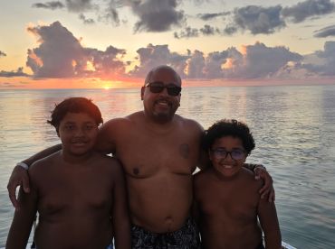 A joyful family poses together at sunset, capturing a memorable moment on the water — perfect for family vacations and bonding experiences.