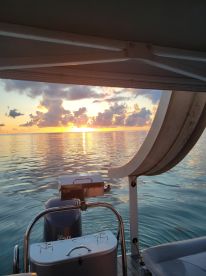A serene sunset view from the deck of a boat, showcasing the tranquil waters and vibrant sky — perfect for peaceful evening cruises.