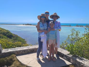 A joyful family poses together against a stunning coastal backdrop, capturing a memorable moment during their beach adventure.