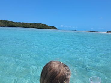 A child enjoys the stunning view of crystal-clear waters and lush islands, capturing the essence of a perfect beach day.