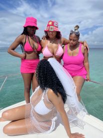 A group of friends celebrates a bachelorette party on a boat, showcasing vibrant pink outfits against a stunning ocean backdrop — perfect for unforgettable moments on the water.