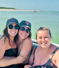 Three friends enjoy a sunny day on a boat, capturing a joyful moment together — perfect for celebrating special occasions or just having fun on the water.