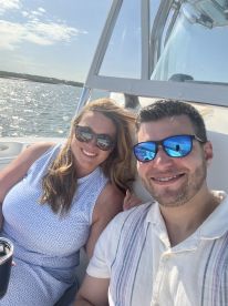 A cheerful couple enjoys a sunny day on the water, capturing a perfect moment aboard their boat — ideal for romantic outings or fun adventures.
