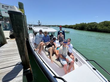 A cheerful group of friends relaxes on a boat at the dock, ready for a day of adventure on the water under the bright sun.