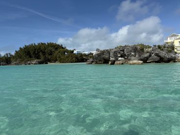 A stunning view of the turquoise waters and rocky coastline in Bermuda, showcasing the natural beauty of the area — perfect for island hopping and scenic tours.