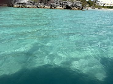 An unclear view of turquoise waters and rocky shoreline, lacking identifiable subjects or details.