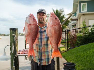 A proud angler displays his impressive catch of red snapper, showcasing the thrill of a successful fishing trip.
