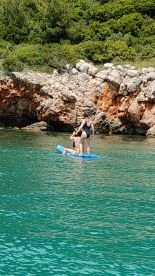 A couple enjoys paddleboarding in crystal-clear waters, showcasing a fun and adventurous day on the water surrounded by stunning natural scenery.