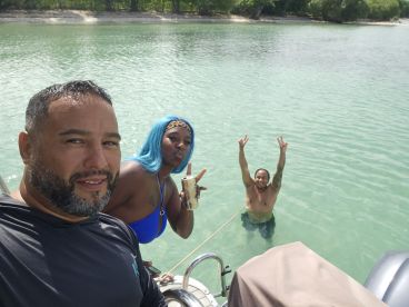 A lively group enjoys a fun day on the water, with one person swimming and others celebrating on the boat — perfect for memorable outings and adventures.