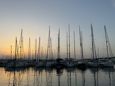 A serene sunset view of a marina filled with sailboats and yachts, reflecting beautifully on the calm water — perfect for showcasing the tranquility of boating life.