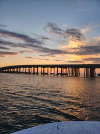 A stunning sunset view of a bridge over calm waters, capturing the serene beauty of the evening sky — perfect for scenic boat rides.