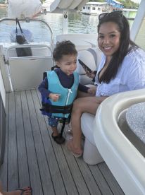 A joyful moment captured inside a boat, featuring a woman and a young child in life jackets, showcasing family fun on the water.