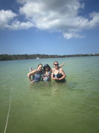 A joyful group of friends enjoys a refreshing swim in shallow waters, perfect for a fun day out on the beach.