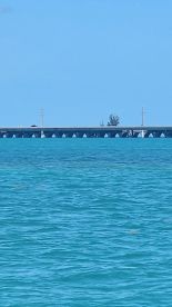 An unclear image showing a distant structure over turquoise waters, lacking identifiable features or subjects.