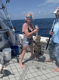 A woman proudly displays her catch while fishing on a boat, showcasing the excitement of a successful day on the water.