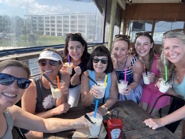A cheerful group of friends enjoys refreshing cocktails together, capturing a perfect moment of celebration and camaraderie on the water.