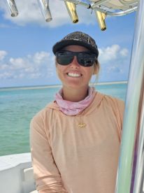 A smiling woman poses on a boat with a beautiful ocean backdrop, showcasing the joy of boating adventures. Perfect for capturing the spirit of fun on the water.