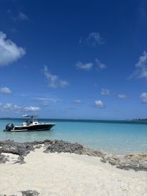 A sleek speedboat is docked in the shallow turquoise waters, surrounded by a serene beach landscape — perfect for a day of relaxation and exploration.