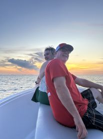A couple enjoys a serene sunset on a boat, creating a perfect backdrop for romantic moments on the water.