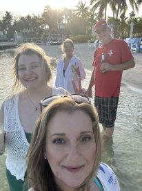 A cheerful group enjoys a beach day, capturing memories with drinks in hand as the sun sets in the background — perfect for celebrations and fun outings.
