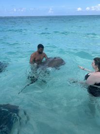 A thrilling encounter as two individuals interact with stingrays in the crystal-clear waters, showcasing the beauty of marine wildlife in a unique experience.