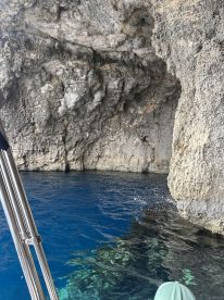 A stunning view of a cave with crystal-clear blue water, showcasing the natural beauty of the surroundings — perfect for exploring hidden gems on a boating adventure.