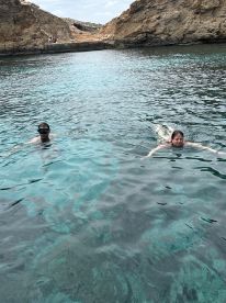 Two swimmers enjoy the crystal-clear waters surrounded by stunning rocky scenery, perfect for a refreshing aquatic adventure.