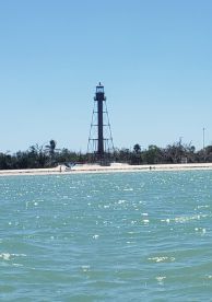 A picturesque view of a lighthouse along the beach, with visitors strolling on the shore — a perfect representation of coastal beauty and exploration.