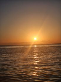 A stunning sunset over calm waters, creating a picturesque scene perfect for evening boat cruises or relaxation on the water.