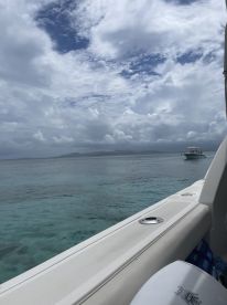 A serene view of a boat cruising through clear turquoise waters, with dramatic clouds overhead, perfect for showcasing the beauty of a day on the water.