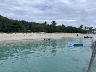A lively scene at a beach with a group enjoying the water, including children swimming and jet skis nearby — a perfect sandbar stop for family fun.