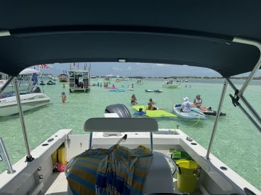 A vibrant scene at a sandbar with groups enjoying the water, swimming, and relaxing on various watercraft — a perfect day for fun in the sun.