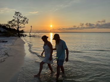 A couple enjoys a romantic walk along the beach at sunset, creating a picturesque moment perfect for memorable getaways.
