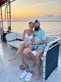 A couple enjoys drinks together on a boat at sunset, creating a romantic atmosphere perfect for special occasions or sunset cruises.
