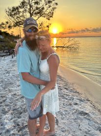 A couple embraces on the beach at sunset, capturing a romantic moment perfect for celebrations and special occasions.