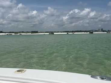 A scenic view of a sandbar with various boats anchored nearby, showcasing a lively beach atmosphere perfect for water activities and relaxation.