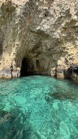 A stunning view of a coastal cave surrounded by crystal-clear turquoise waters, perfect for exploring and enjoying the natural beauty of the area.