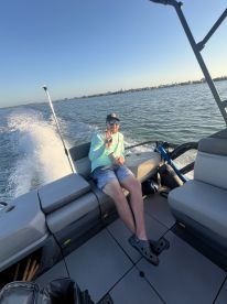 A man relaxes on the deck of a boat, enjoying a scenic day on the water — perfect for leisurely outings and fun adventures.