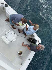 A group of friends enjoys a fishing trip on a boat, showcasing their catch in a bucket — a perfect day on the water filled with camaraderie and adventure.