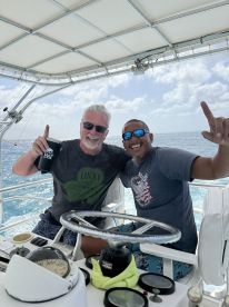 Two friends celebrate aboard a boat, enjoying the sunny day at sea — a perfect moment of camaraderie and fun on the water.