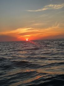 A breathtaking sunset over the ocean, showcasing vibrant colors reflecting on the water — a perfect backdrop for evening boat cruises.