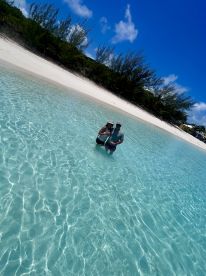 A couple enjoys a sunny day in shallow, crystal-clear waters at a picturesque beach, perfect for romantic getaways and memorable celebrations.