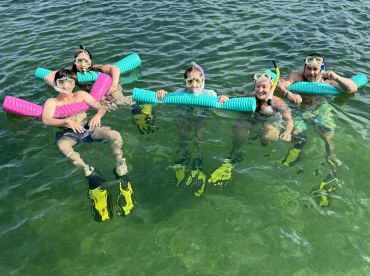 A lively group enjoys snorkeling in clear waters, showcasing fun and adventure in a tropical setting.