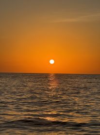 A breathtaking sunset over the ocean, casting golden reflections on the water — a perfect backdrop for evening boat cruises.