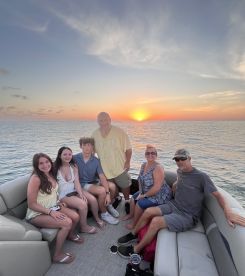 A joyful family gathers on a pontoon boat at sunset, capturing a memorable moment together on the water — perfect for family outings and celebrations.